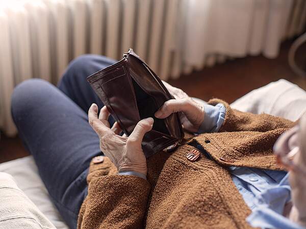 Une retraitée regarde son sac à main vide