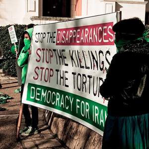 Des femmes brandissent une banderole contre la torture et les meurtres commis par l'État en Iran.