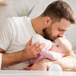 Un père donne du lait à son bébé.
