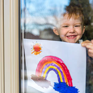 Un garçon accroche un arc-en-ciel à la fenêtre