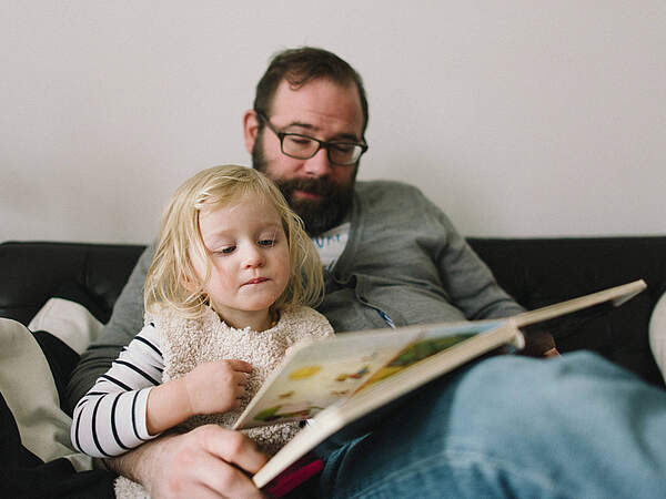 Un homme lit à un enfant.
